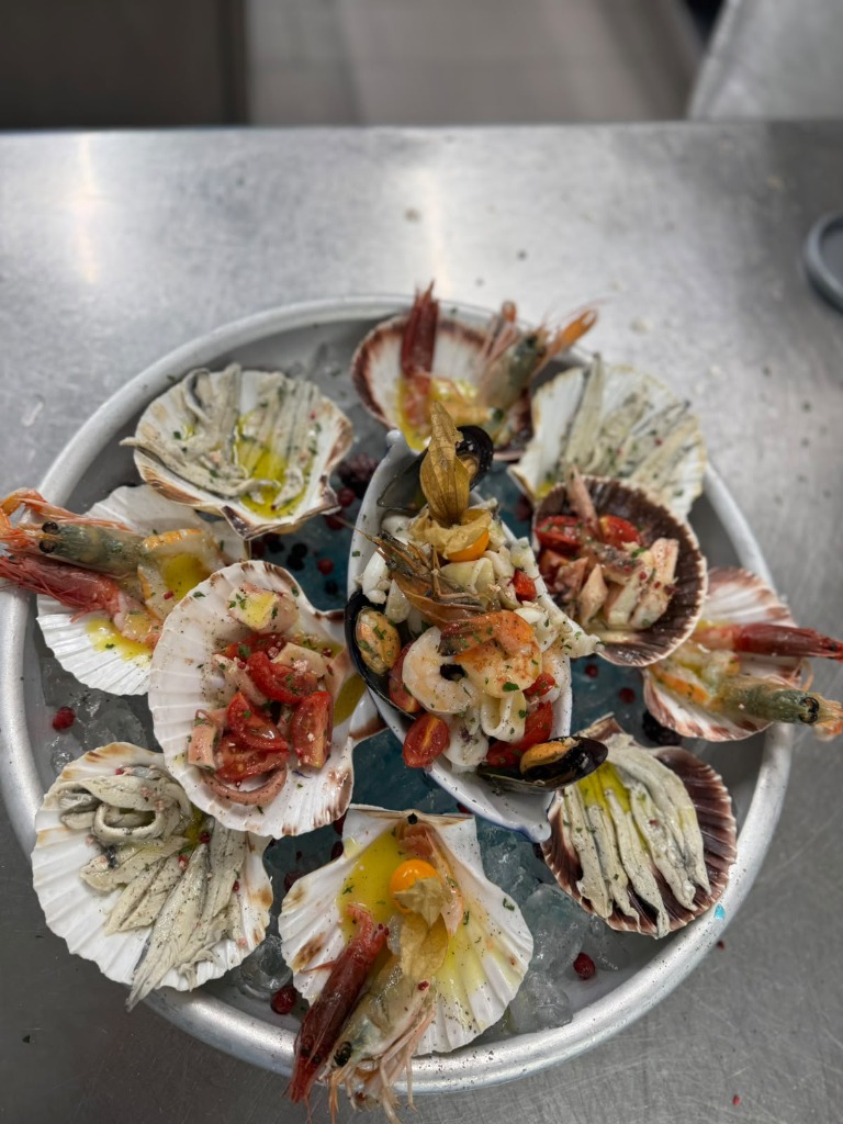 Piatto di crudi di mare con capasanta, gamberi e marinati freschi
